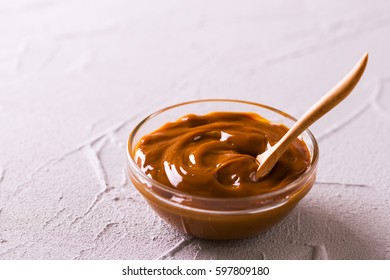 Bowl Of Homemade Melted Caramel Sauce On Stone Background