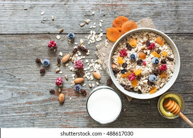 bowl of homemade muesli with nuts, berries, dried fruits, glass of milk and honey. healthy breakfast. top view - Shutterstock ID 488617030