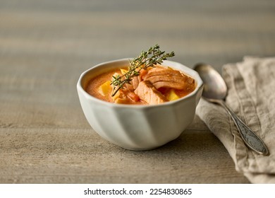 bowl of homemade salmon and tomato soup on wooden kitchen table