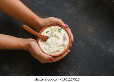 Bowl of homemade sour cream curd yogurt Dahi fresh herbs curry leaf Kerala, India. woman hand take dairy product obtained coagulating milk process curdling. probiotic food tasty curd rice curry spices