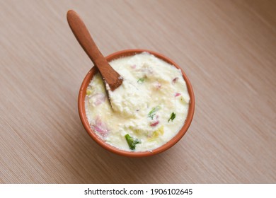 Bowl of homemade sour cream curd yogurt Dahi fresh herbs curry leaf Kerala, India. woman hand take dairy product obtained coagulating milk process curdling. probiotic food tasty curd rice curry spices