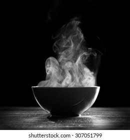 Bowl of hot soup on black background