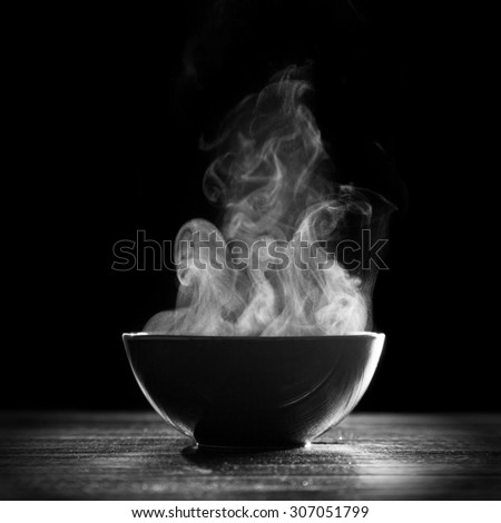 Bowl of hot soup on black background