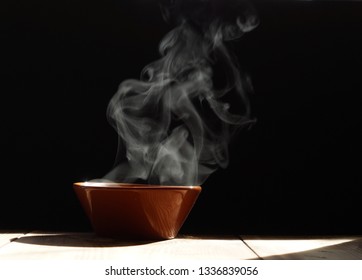 bowl of hot soup with steaming on wooden table on black background - Shutterstock ID 1336839056