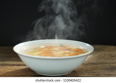 Bowl Of Hot Soup With Steaming On Wooden Table On Black Background Selective Focus. Vegetables And Ground Pork, I Steaming. Hot Food Concept.