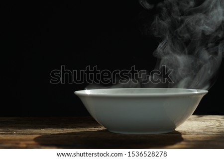 bowl of hot soup with steaming on wooden table on black background selective focus. hot food concept.
