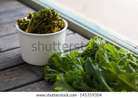 bowl of kale chips next to fresh kale