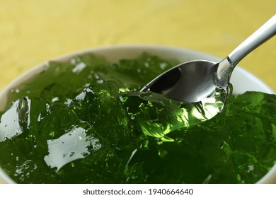 Bowl Of Kiwi Jelly With Spoon On Yellow Textured Background, Close Up
