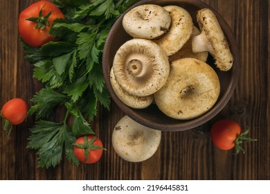 A Bowl With Large Wild Mushrooms, Vegetables And Celery Leaves On A Wooden Table. Vegetarian Food From The Forest. Flat Lay.