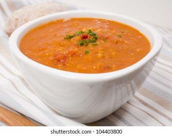 A Bowl Of Lentil And Tomato Soup Garnished With Chives.