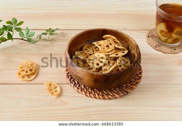 a bowl of lotus root chips accompanied with a\
glass of lotus root drink 