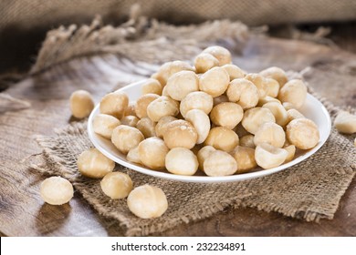 Bowl with Macadamia nuts on dark rustic wooden background