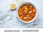 Bowl of manhattan clam chowder on a white marble background, horizontal shot with space, above view