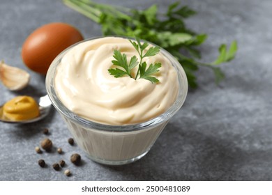 Bowl with mayonnaise and ingredients for cooking on gray background