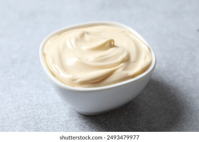 Bowl with mayonnaise on gray background