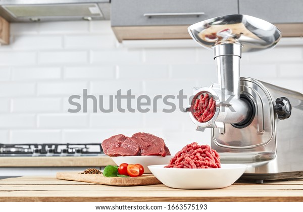 Bowl of mince with electric meat grinder in\
kitchen interior