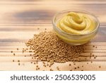 Bowl with mustard and seeds on wooden background