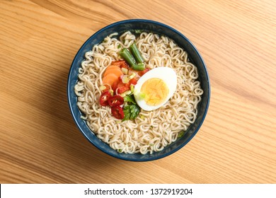 Bowl Of Noodles With Broth, Egg And Vegetables On Wooden Background, Top View