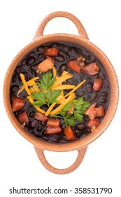 Bowl Of Nutritious Black Bean Soup Garnished With Cheddar Cheese, Fresh Parsley And Tomato Viewed Close Up From Above Isolated On White