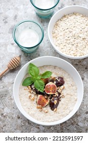 Bowl Of Oatmeal With Figs, Date Fruits And Honey, High Angle View On A Light-brown Granite Background, Vertical Shot