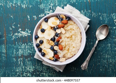Bowl of oatmeal porridge with banana, blueberries, almonds, coconut and caramel sauce on teal rustic table, hot and healthy food for Breakfast, top view, flat lay - Shutterstock ID 448097557