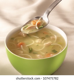 Bowl On A Table With Chicken Soup And A Spoon Hovering Above