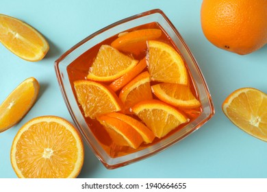 Bowl of orange jelly with orange slices on blue background