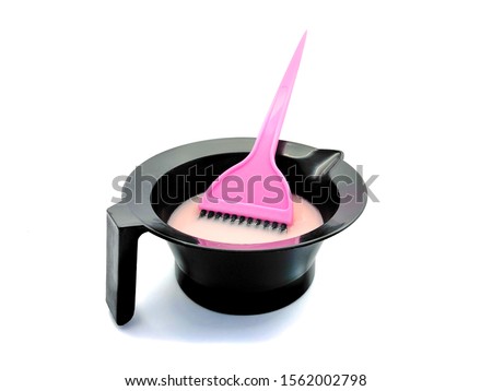 Bowl for paint and pink brush isolated on a white background. Hairdressing set for hair coloring. Composition of tools for a beauty salon. Bowl with pink hair dye.