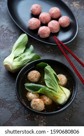 Bowl of panasian meatball soup with pak-choi, studio shot over brown stone background
