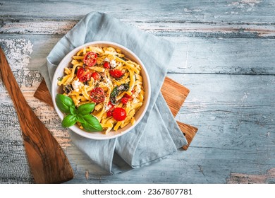Bowl of pasta, noodles, swabian spaetzle, with spinach and cherry tomatoes on rustic wooden table, top view - Powered by Shutterstock
