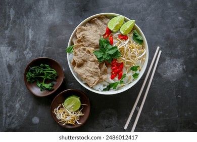 A Bowl Pho Bo traditional Soup with beef, rice noodles, ginger, lime, chili pepper in bowl. Close up. Vietnamese cuisine served on black background - Powered by Shutterstock