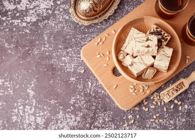 Bowl with pieces of tasty marble halva on grunge background