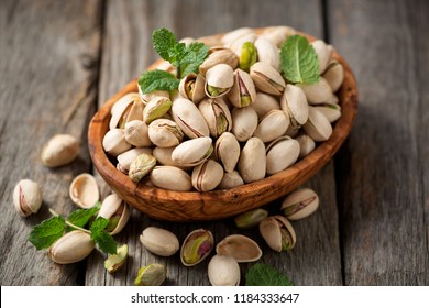 Bowl with pistachios on a wooden table.