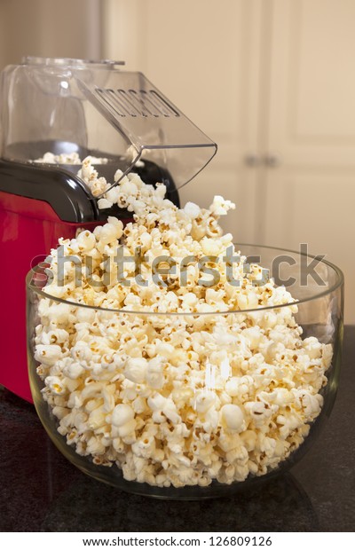 Bowl of popcorn with popcorn machine\
on a kitchen bench.  Healthy home-made\
snacking.