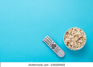 Bowl With Popcorn And Remote Control For TV On A Blue Background. Concept Home Theater, Movie, Leisure. Flat Lay, Top View