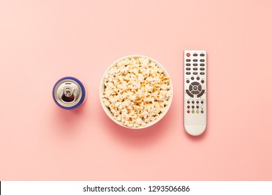 A Bowl Of Popcorn, A TV Remote, A Jar Of Drink On A Pink Background. The Concept Of Watching TV, Film, TV Series, Sports, Shows. Flat Lay, Top View.