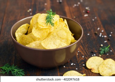 bowl of potato chips with dill on a dark background