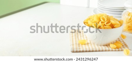 Bowl with raw conchiglie pasta on light table. Banner for design