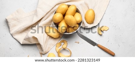 Bowl with raw potatoes and knife on light background