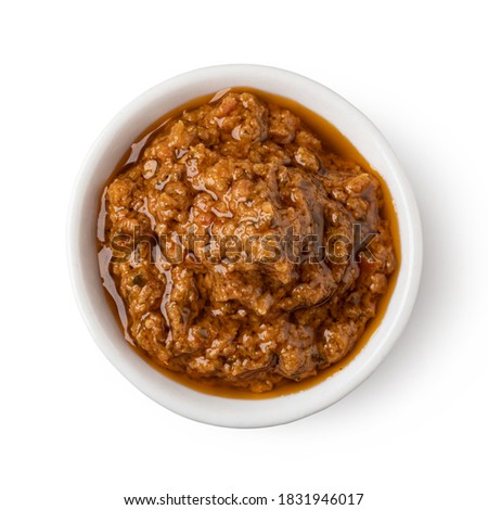 Bowl with red pesto sauce isolated on white background
