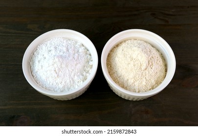 A Bowl Of Refined Flour And A Bowl Of Whole Wheat Flour Isolated On Black Wooden Background