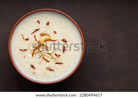 Bowl with rice pudding on dark background. Creamy rice kheer with cashew nuts and almonds. Copy space. Top view