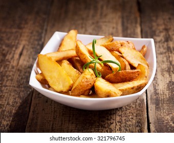 Bowl Of Roasted Potatoes With Rosemary On Wooden Table