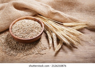 Bowl of rye grains and ears on wooden table - Shutterstock ID 2126210876