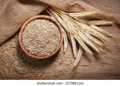 Bowl of rye grains and ears on wooden table, top view - Shutterstock ID 2173861161