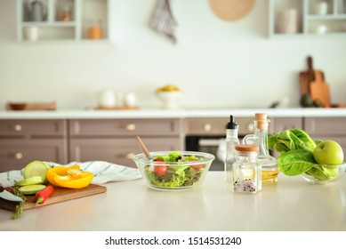 Bowl With Salad And Ingredients On Kitchen Table
