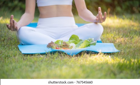 Bowl with salad on green grass with girl posting meditation on blue yoga map, healty food, selective focus,coply space.