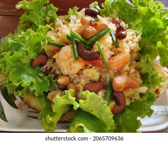 A Bowl Of Salad With Pineapple, Rice, Nuts And Fish