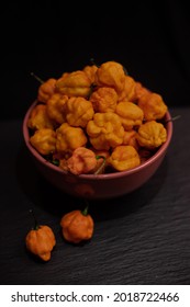 bowl of SB7J yellow peppers, habaneros, ghost peach peppers, extreme hot peppers on a black table