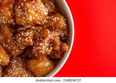 Bowl Of Sesame Chicken On A Bright Red Background